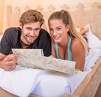 Fahrradfahrer, Fahrrad, Tour planen im Bett des Hotel Arthus, Fahrradkarte, Paarurlaub