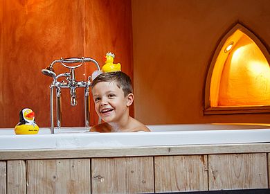 Kinder im Hotel Arthus, Badespaß, Freistehende Badewanne im Holzzuber, kleiner Ritter, Quietscheentchen, Quietscheente